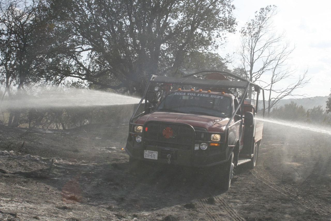 An ECCA brush truck spraying water across a burned field of mesquite.